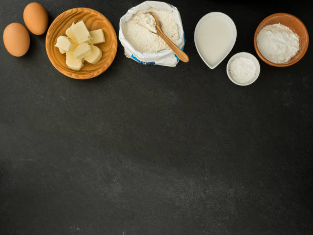 eggs, butter, milk, sugar, baking powder and flour on slate background
