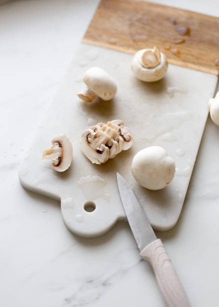 Fresh sliced champignon mushrooms on cutting board.