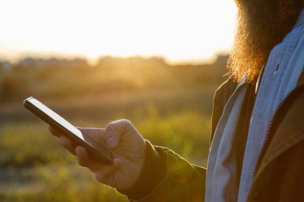 istock A man´s hand holding a cell phone in the field at sunset 1218188683