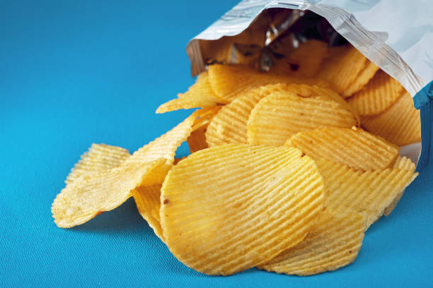 Potato chips in a bag or package spill out on the table Potato chips in a bag or package spill out on the table. Macro close up view. potato chip photos stock pictures, royalty-free photos & images
