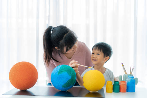 asian preschool student boy with mother painting the moon learning about the solar system at home, homeschooling and distance learning. - earth globe mother child imagens e fotografias de stock