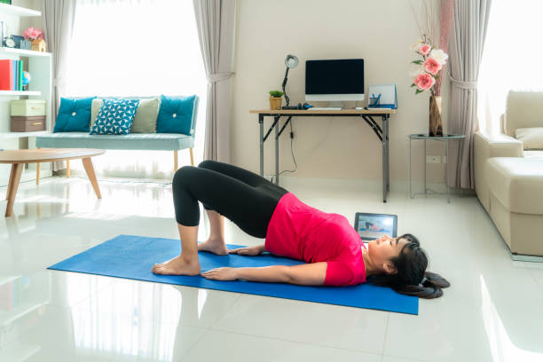 istock Asian woman making yoga exercise for step away from their computers to take mid-day exercise breaks via livestream videos classes on digital tablets during working from home. 1218190213
