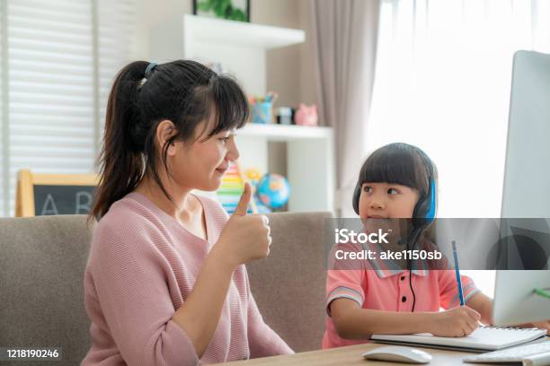 Asian Girl Student With Mother Thumb Up To Her Daughter While Video Conference Elearning With Teacher On Computer In Living Room At Home Homeschooling And Distance Learning Online Education And Internet Stock Photo - Download Image Now