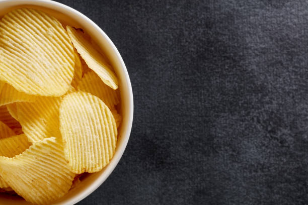 istock Crispy potato chips in a white bowl on black background 1218191562