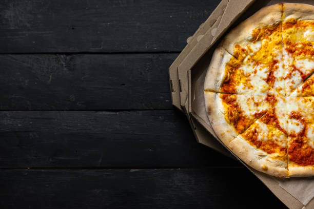 istock Pizza margherita in an open delivery box, dark backdrop with text space. 1218192350