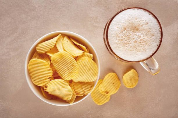 Potato chips and glass of beer on rustic wooden background Potato chips and glass of beer on rustic wooden background. Top view pub table top view stock pictures, royalty-free photos & images