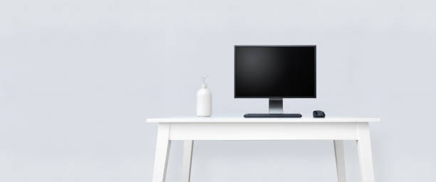istock Clean white table with desktop computer and bottle with hand disinfection liquid. 1218193086