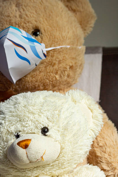 istock Generic bear toy in couch wearing handmade paper mask 1218193484