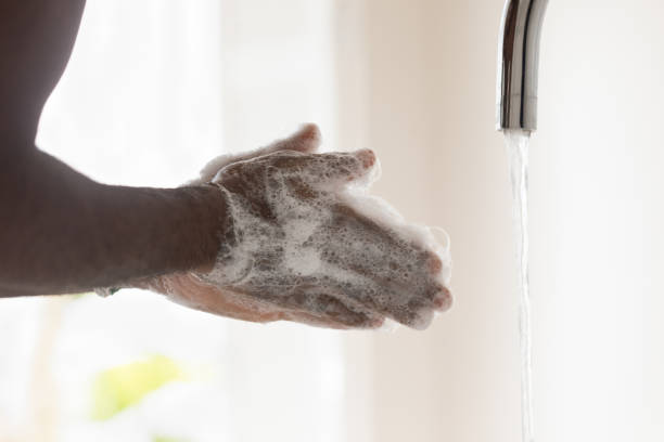 молодой афроамериканец моет руки пузырчатым антибактериальным мылом. - faucet stream water bathroom стоковые фото и изображения