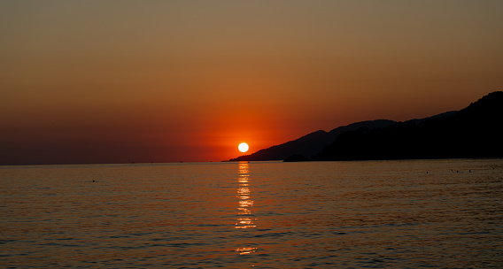 Beautiful summer sunset on sea with mountains. Scenic detailed background. High resolution photo