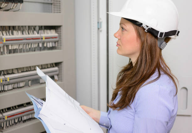 istock Female engineer looking at blueprints in power substation. 1218195582