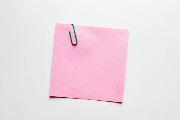 istock Blank pink note paper or notepad with a yellow paper clip on white background with copy space 1218196066