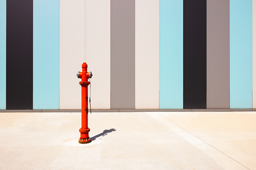 Fire Hydrant on Sidewalk in front of black, gray and turquoise colored wall.
