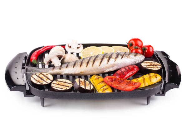 Grilled fish and vegetables on an electric grill. Isolated in a white background. Close-up.
