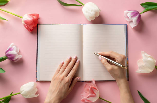 istock woman's hands writing with a pen in an open blank notebook on a pink background 1218197622