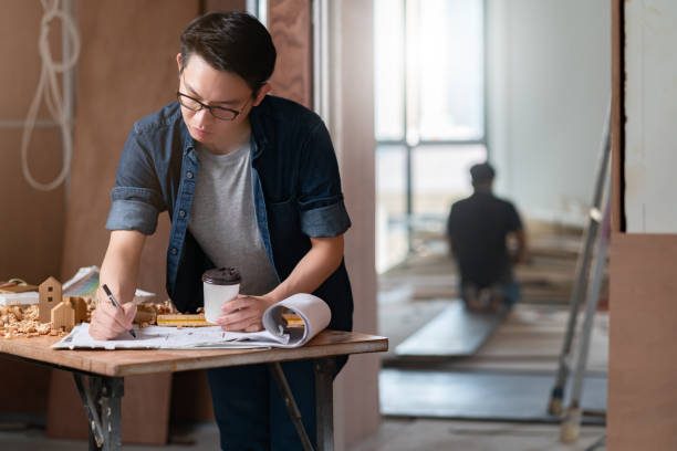 istock asian attractive glasses interior designer working at house site renovation construction progress with smile and confident at desk with blue print and drawing tool 1218198812