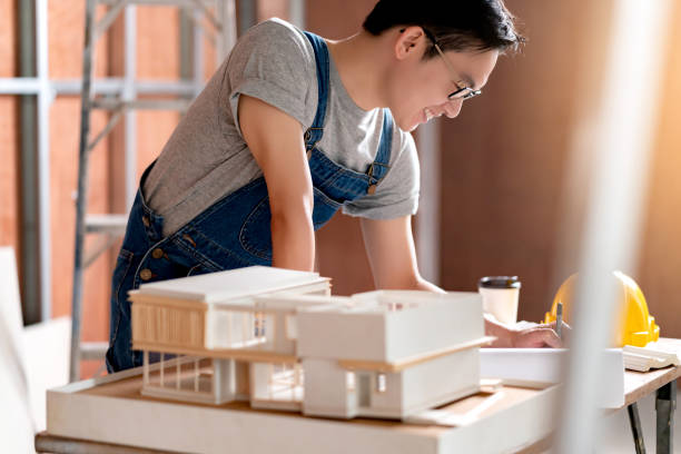 istock asian attractive glasses interior designer working at house site renovation construction progress with smile and confident at desk with blue print and drawing tool 1218198852