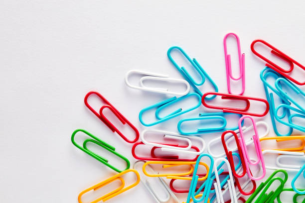 Heap of colorful paper clips on white background with copy space. Heap of colorful paper clips on white background with copy space. Flat lay macro view. paper clip office supply stack heap stock pictures, royalty-free photos & images