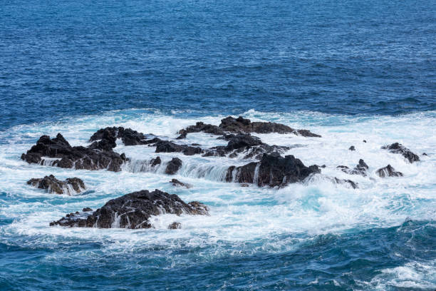 formazione rocciosa vulcanica, scogliere di lava nera sulla costa rocciosa con onde bianche schiacciante sull'oceano atlantico. sfondo cielo blu. la palma, isole canarie. - rocky coastline spain la palma canary islands foto e immagini stock