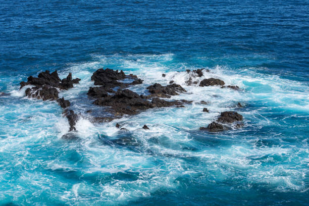 formazione rocciosa vulcanica, scogliere di lava nera sulla costa rocciosa con onde bianche schiacciante sull'oceano atlantico. sfondo cielo blu. la palma, isole canarie. - rocky coastline spain la palma canary islands foto e immagini stock