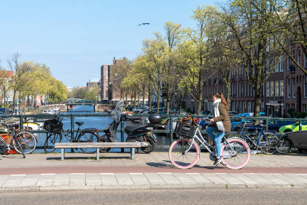 Canal during a bright spring day in Amsterdam, Netherlands with a cyclist going over a bridge on Kostverlorenvaart canal.