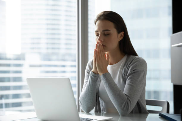 istock Religious female employee praying to god at workplace 1218204695