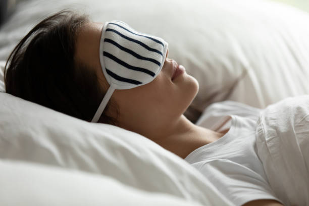 istock Young woman in sleeping mask relaxing in comfy bed 1218204748
