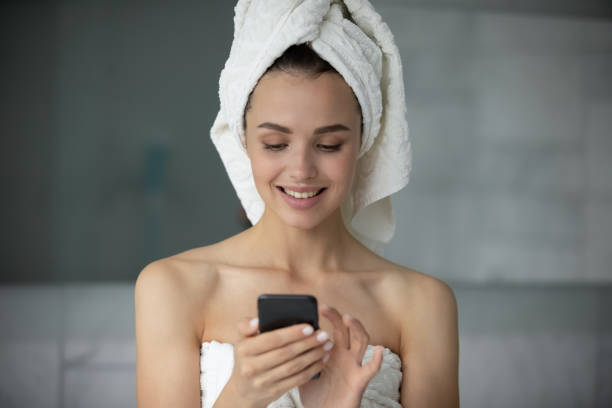 istock Young woman using cellphone in bathroom after shower 1218204767