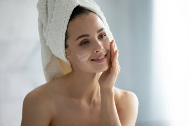 istock Millennial female using facial moisturizing cream in bathroom 1218204770