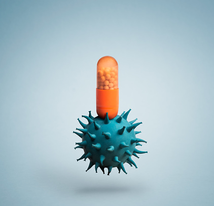 Medicine capsule pill on top of blue virus resembling coronavirus