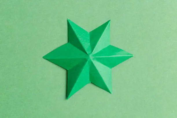 Photo of Green paper star over green background