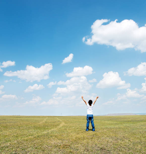 istock Little boy arms raised under blue sky 1218209023