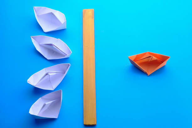 istock Leadership concept using orange paper ship among white 1218213530