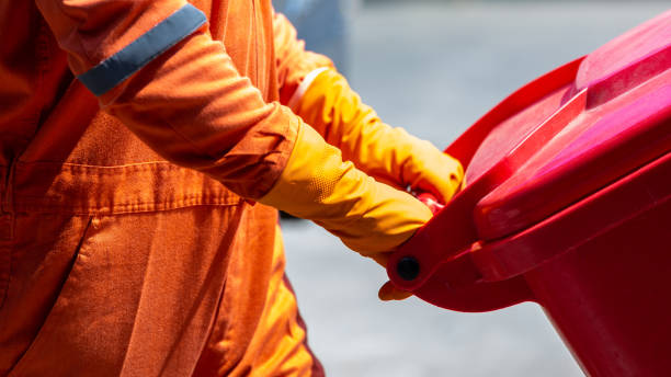 homem em traje de proteção e recipiente de descarte de resíduos infecciosos, resíduos infecciosos devem ser descartados no saco vermelho de lixo, equipamento de proteção coronavírus em lixeira médica. - hazardous materials protection - fotografias e filmes do acervo