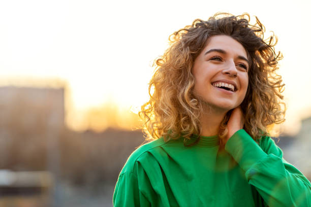 портрет молодой женщины с вьющимися волосами в городе - women smiling blond hair cheerful стоковые фото и изображения