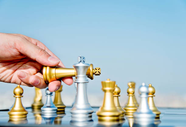 Man hand moving golden king in chess game.