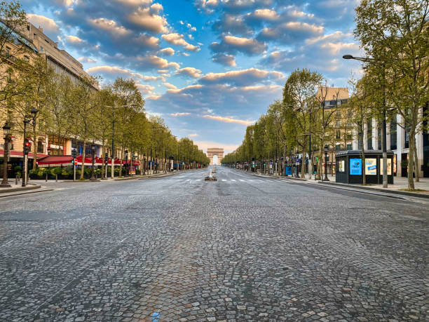 Champs-Elysées completely empty during the health crisis Paris, France - April 11, 2020 - View of the avenue des Champs-Elysées completely empty during the confinement linked to the health crisis of the coronas virus. In the foreground, the cobblestones of the avenue covering the road and the first stores located on the sides of the Champs-Elysées are visible. In the background, the Arc de Triomphe under a sunrise is visible. arc de triomphe paris photos stock pictures, royalty-free photos & images