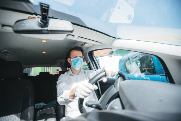 istock Man With Protective Face Mask Driving The Car 1218221280