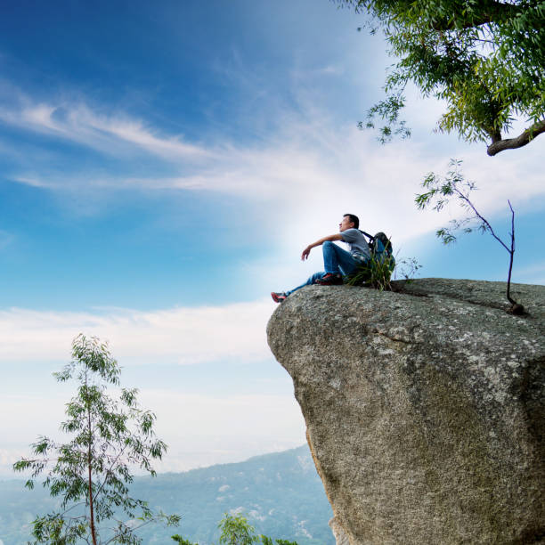 istock Hiking man sitting on cliff enjoy the view 1218221900
