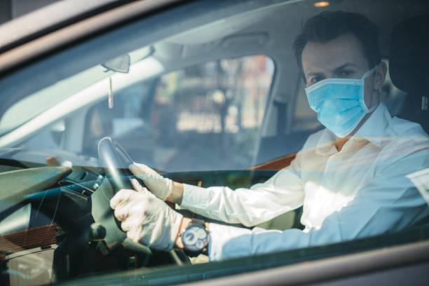 istock Man With Protective Face Mask Driving The Car 1218221943