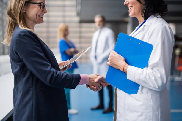 arts die aan farmaceutische vertegenwoordiger spreekt, die handen schudt. - verkoopster stockfoto's en -beelden