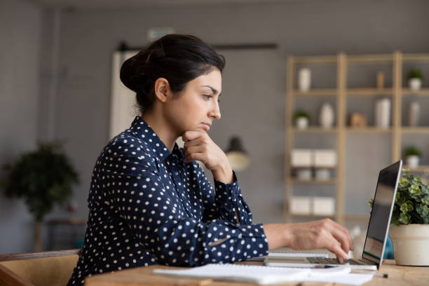 istock Thoughtful Indian woman looking at laptop screen, pondering task 1218223732