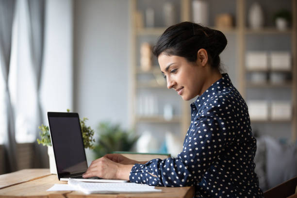 istock Smiling Indian woman working on laptop, reading documents 1218223733