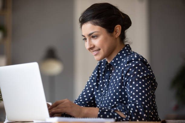istock Smiling Indian young woman working on laptop, looking at screen 1218223735