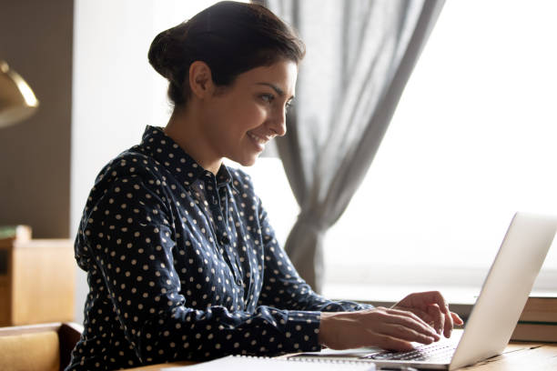 istock Smiling Indian woman working on laptop, typing on keyboard 1218223737