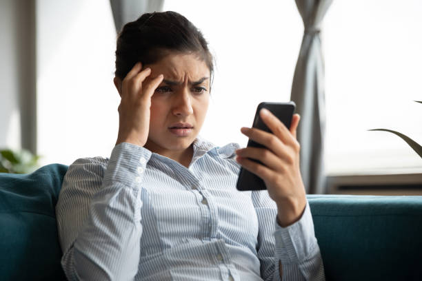 istock Indignant unhappy Indian woman looking at smartphone screen 1218223843