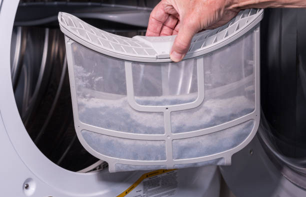 istock Senior man cleaning the lint from the trap in front loading tumble dryer 1218226412