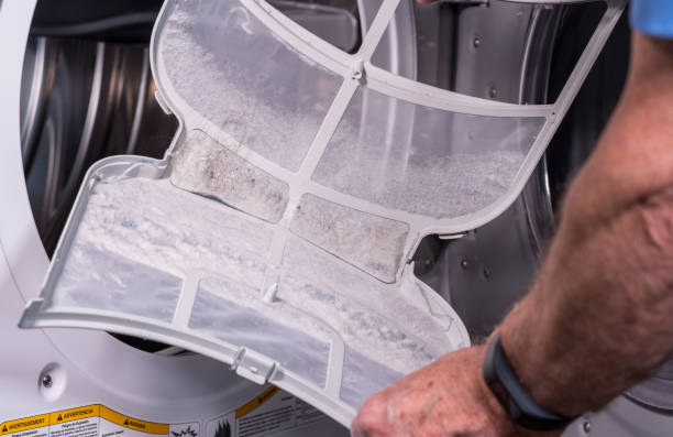 istock Senior man cleaning the lint from the trap in front loading tumble dryer 1218226600