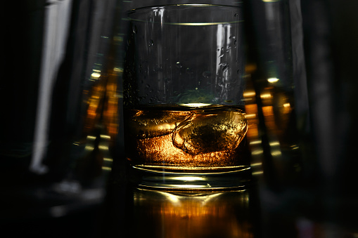 Ice cubes float in a glass with whiskey and blow bubbles