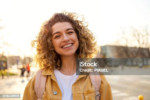 istock Portrait of young woman with curly hair in the city 1218228931